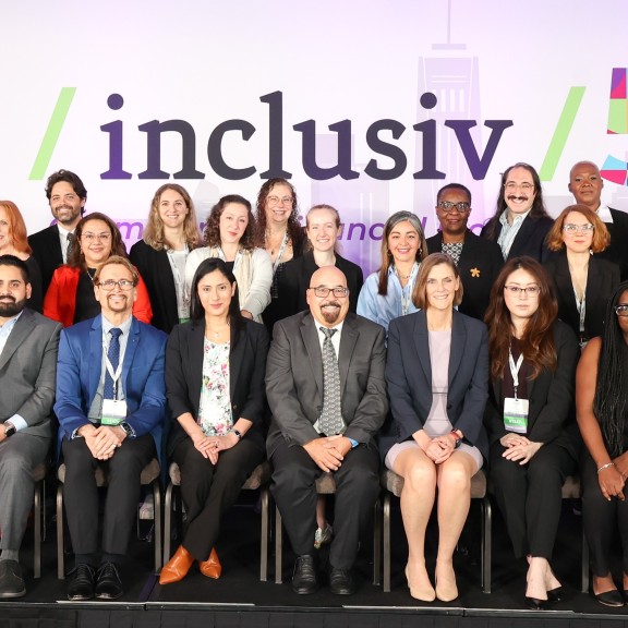 Inclusiv's full staff posed on a stage in front of a 50th anniversary backdrop