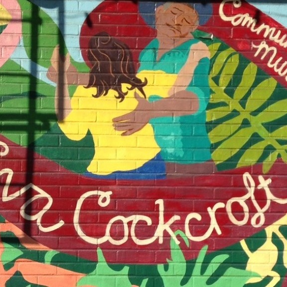 Colorful mural with a plant motif and 2 people dancing, honoring Eva Cockcroft