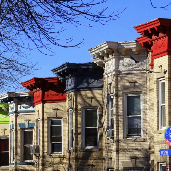 A series of rowhouses with brightly colored eaves in Ridgewood, Queens