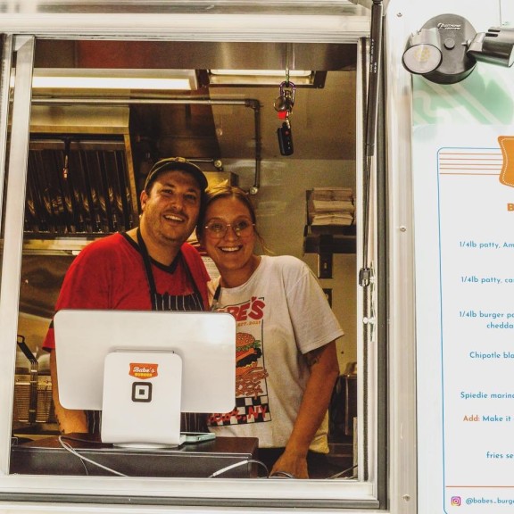 Frank & Lexi - foodtruck owners pose in the window of their truck (Alternatives CU)