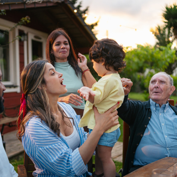 An intergenerational family at a picnic table in front of their home