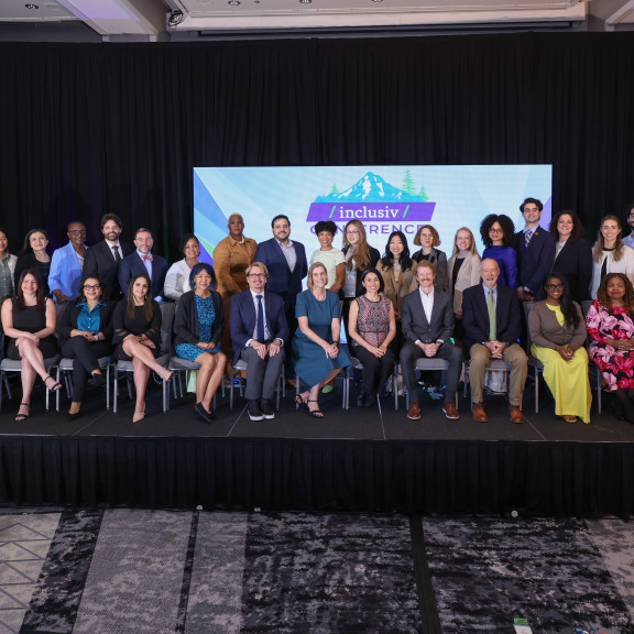 Inclusiv staff posed for a group picture on stage at the 2026 conference