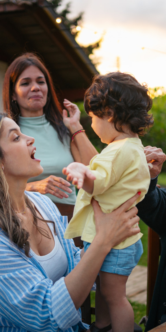 An intergenerational family at a picnic table in front of their home