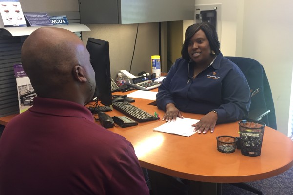 Essential CU staff member sitting at her desk serving a member