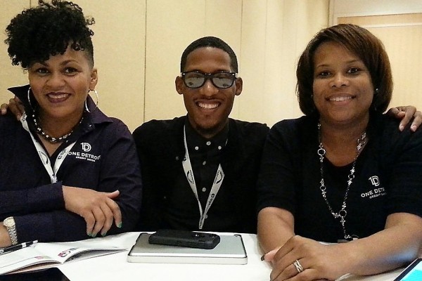 three smiling employees from One Detroit CU siting at a table