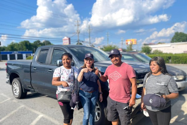 Latino Community Credit Union Members pose with their new truck, alongside a staff member