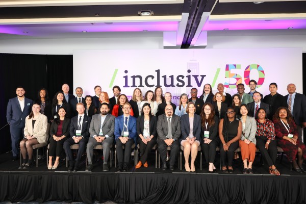 Inclusiv's staff poses onstage in front of our 50th anniversary logo