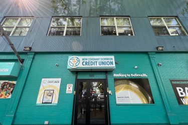 New Covenant Dominion FCU's green brick storefront in the sun