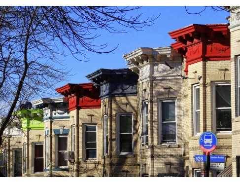 A series of rowhouses with brightly colored eaves in Ridgewood, Queens